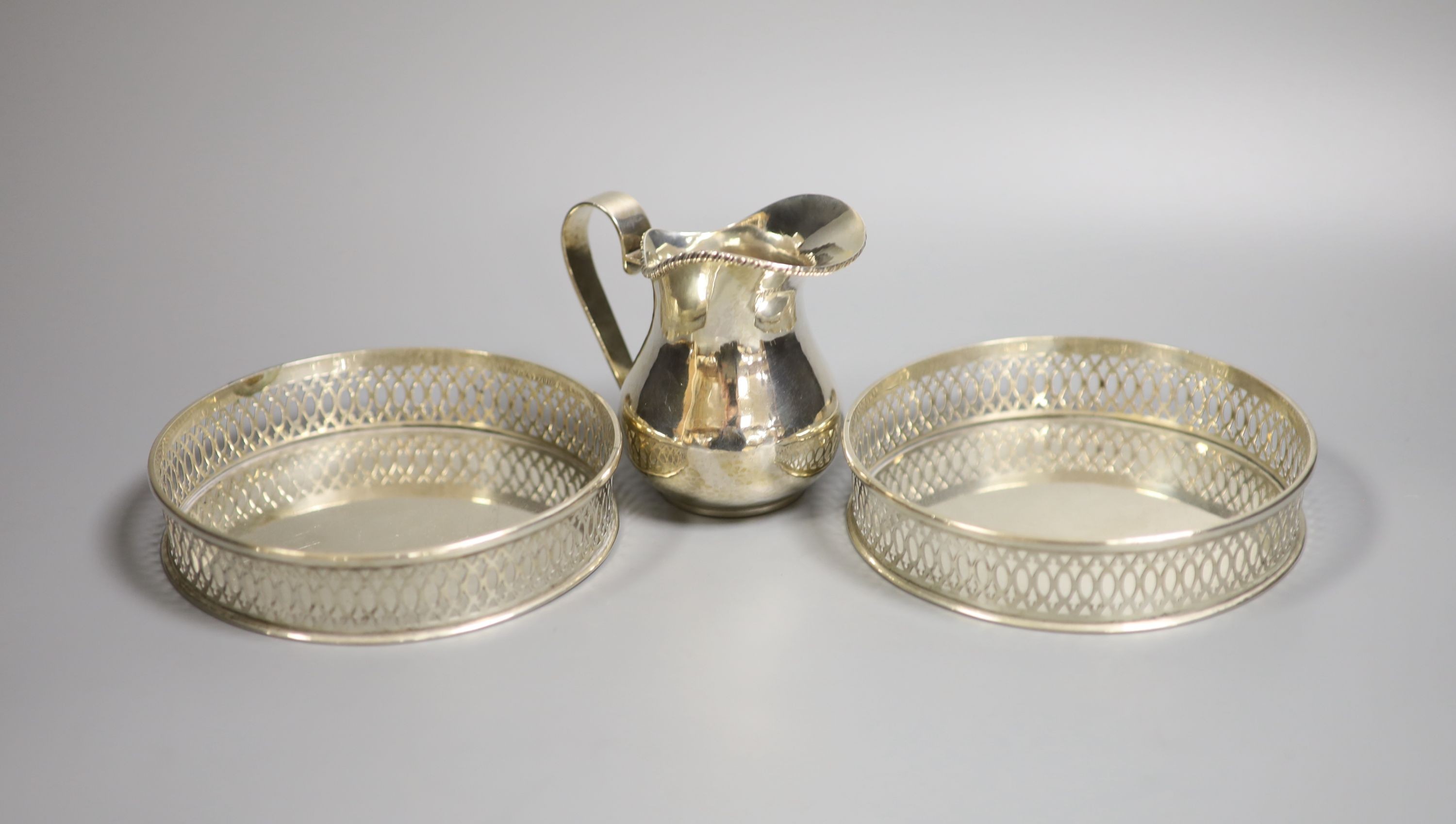 A Continental 800 standard silver cream jug, and a pair of 800 standard wine coasters, 13.6cm, gross 14.5oz.